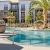 Elegant apartment complex in Sacramento with resort-style pool, modern loungers, and lush palm trees, perfect for luxury living.