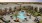 Luxurious apartment complex in Natomas with a stunning courtyard featuring a resort-style pool, palm trees, and cozy lounge areas under a pastel sunset sky.
