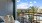 Elegant balcony with modern seating overlooking a resort-style pool and lush palm trees.