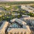 Aerial view of a modern apartment complex in Natomaswith a beautifully landscaped courtyard and pool, surrounded by lush greenery and vibrant cityscape at sunrise.