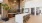 Contemporary apartment interior featuring a luxurious, spacious kitchen with a large marble island, stylish bar stools, elegant gold accent wall, and modern chandelier in Natomas