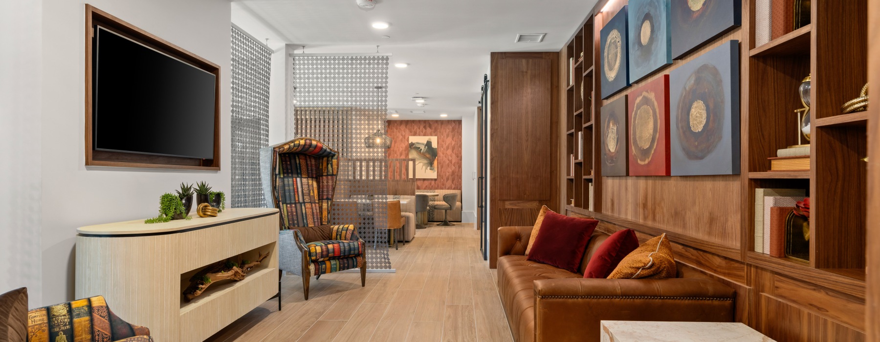 Elegant living space with luxurious leather sofa, chic patterned chairs, and modern decor in a warm, inviting ambiance at Ona in Natomas