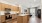 Contemporary open-concept kitchen and living room with sleek wood cabinetry, stainless steel appliances, and bright natural lighting at Ona Natomas