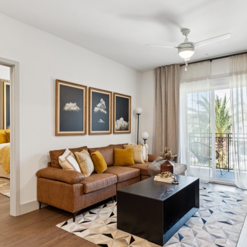 Thoughtfully designed spaces for everyday living Chic living room with a cozy brown sectional sofa, abstract art, and natural light streaming through large windows, opening to a stylish bedroom at Ona Natomas in Sacramento